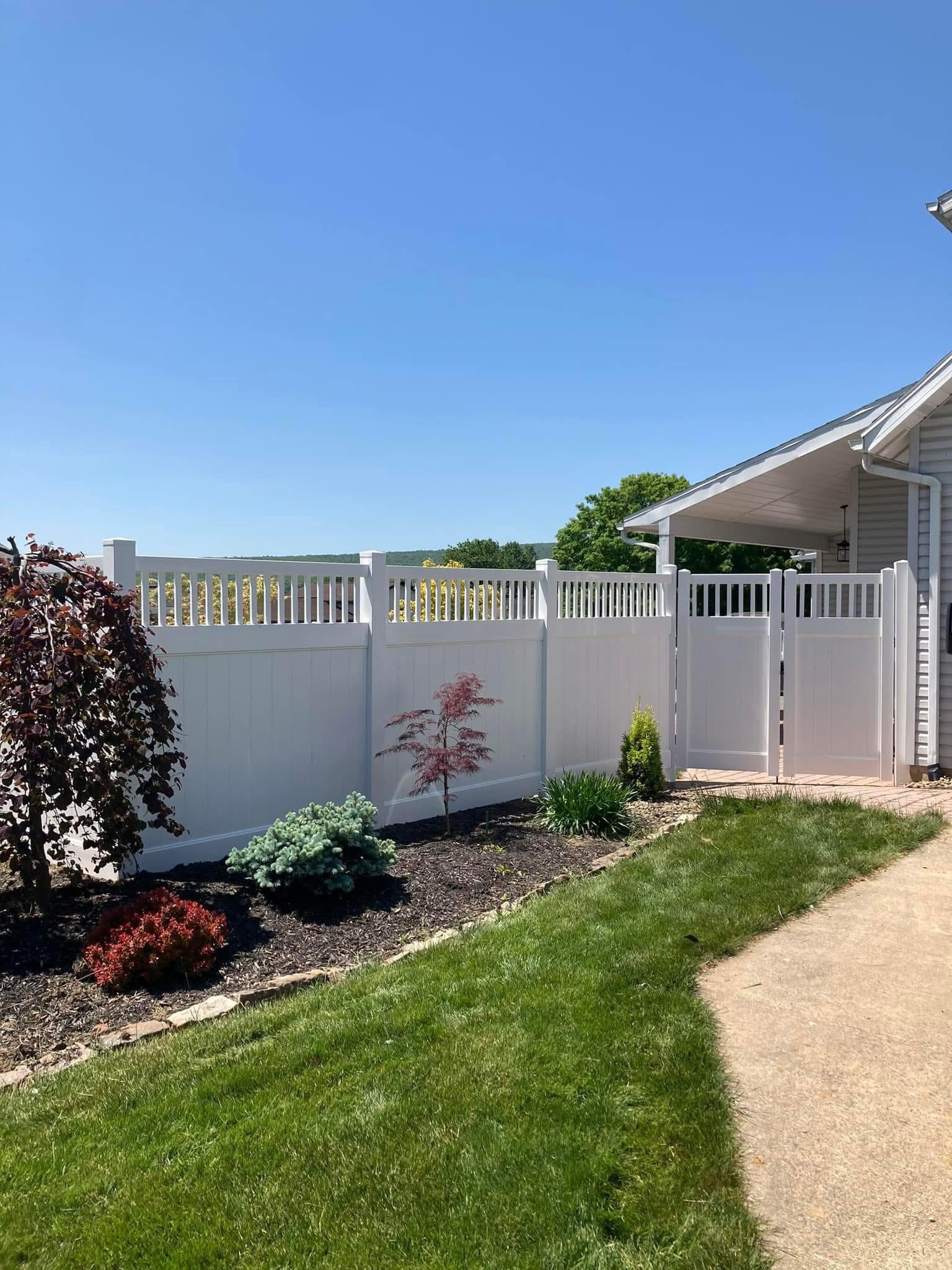 Finished white vinyl fence installation with gates outside a Bloomsburg home