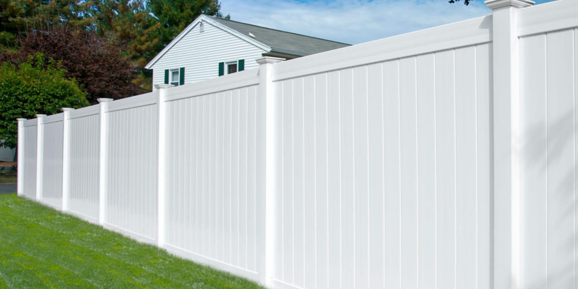 White vinyl privacy fence and gate along a landscaped yard
